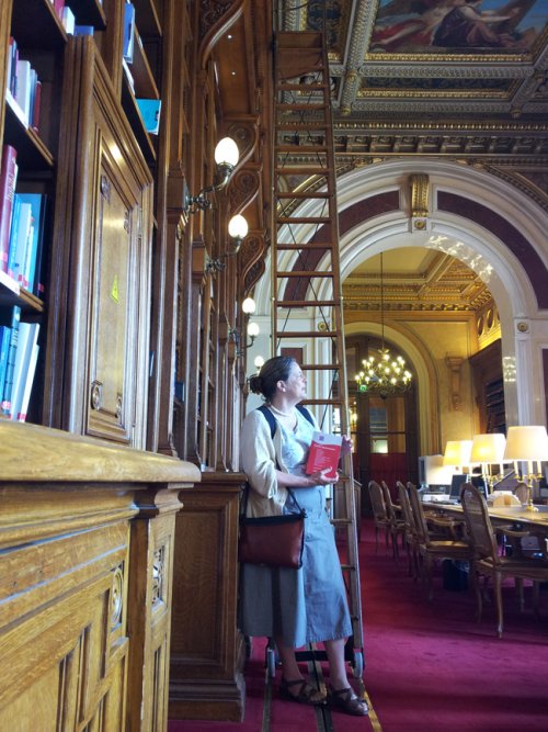Hélène Lipietz dans la bibliothèque, avec le livre « Petit traité du procès administratif » de Rémi Rouquette à la main